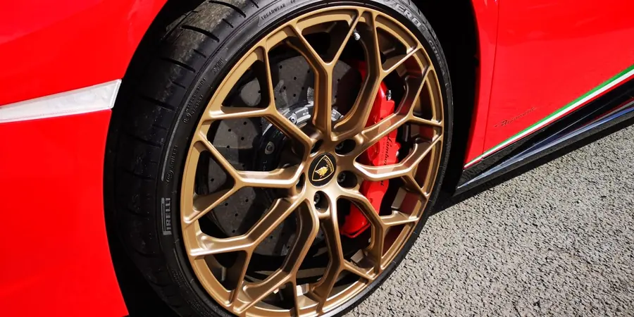 A bronze wheel with a red brake caliper, on a red car